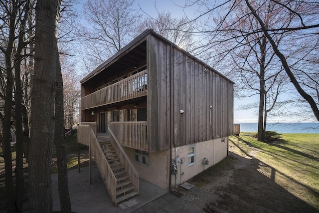 rear view of property with a water view, a balcony, and stairway