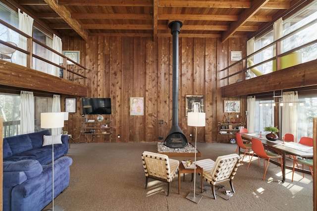 carpeted living room with wood ceiling, a wood stove, and wood walls