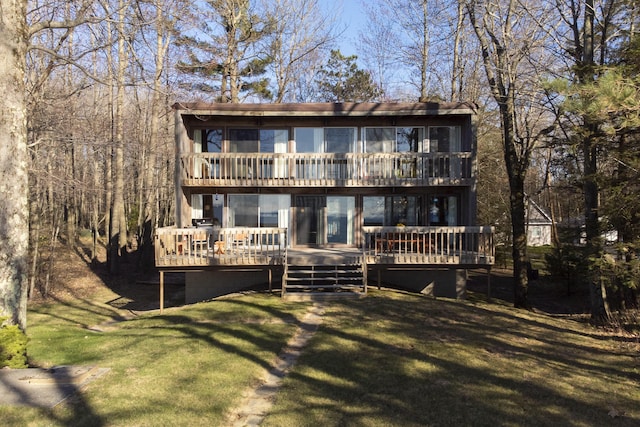 back of property with a balcony, a wooden deck, and a yard