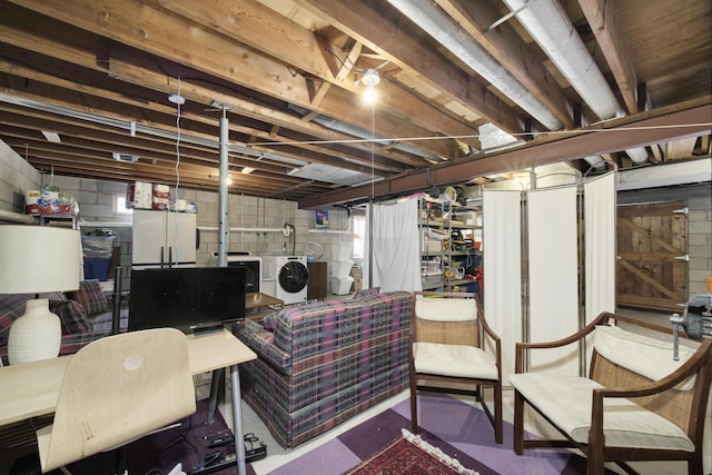 below grade area with freestanding refrigerator, separate washer and dryer, and concrete block wall