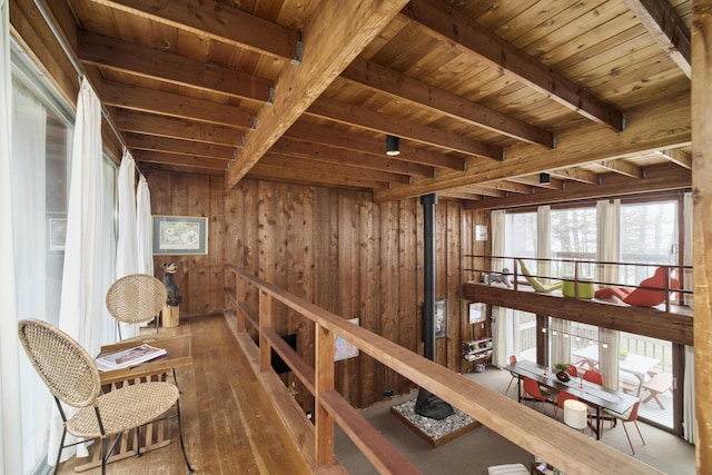 interior space featuring wood ceiling, hardwood / wood-style flooring, beam ceiling, an upstairs landing, and wooden walls