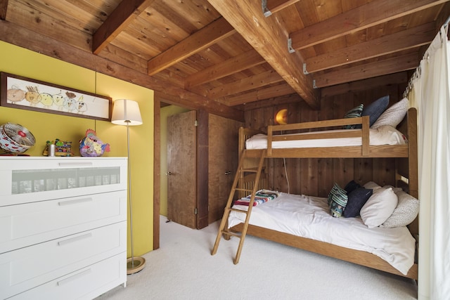 bedroom with wooden walls, wooden ceiling, beamed ceiling, and carpet floors