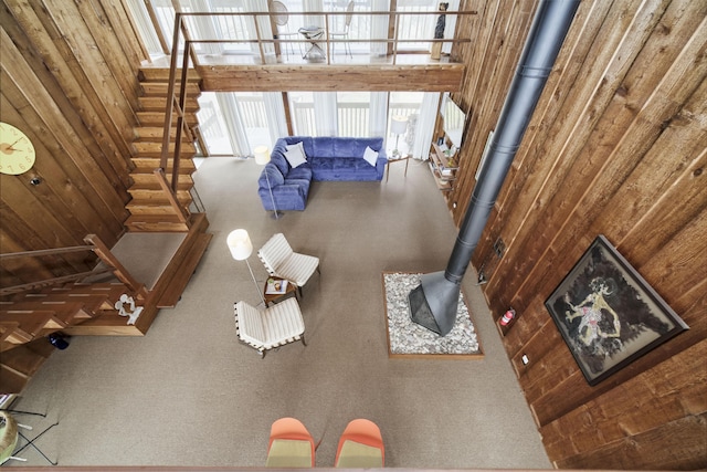 living area featuring stairs, a wood stove, and a towering ceiling
