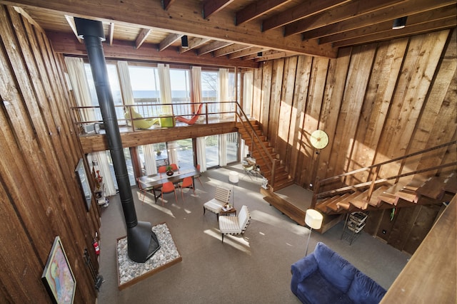 miscellaneous room featuring a wood stove, a water view, wood walls, and beamed ceiling