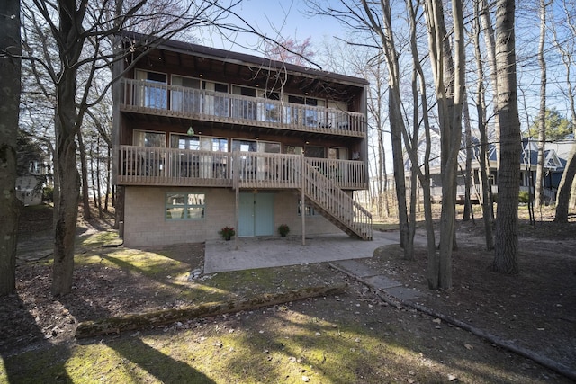 back of property featuring a patio area, a balcony, and stairway