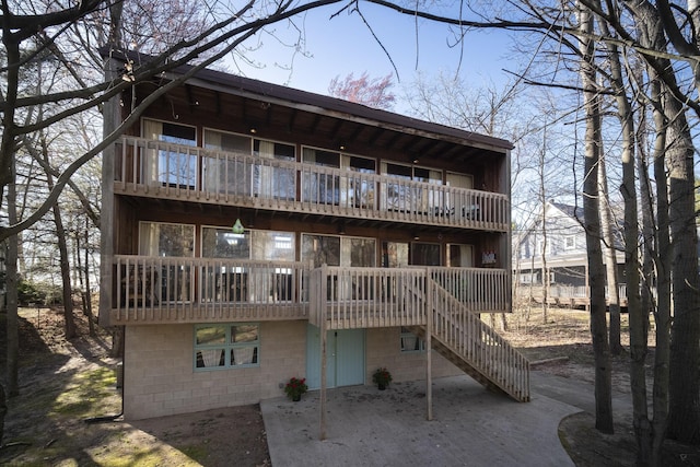 back of house featuring a balcony, a patio area, and stairs