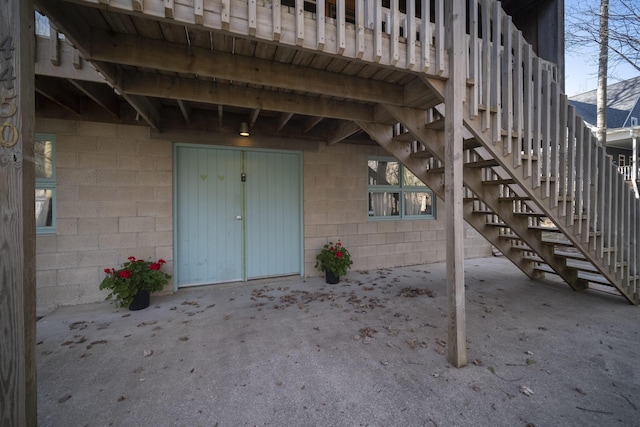 view of exterior entry with a patio and concrete block siding