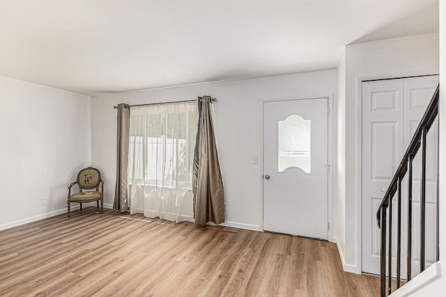 entrance foyer with light wood-type flooring, baseboards, and stairway