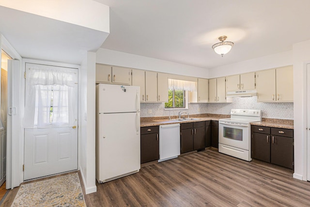 kitchen with white appliances, under cabinet range hood, cream cabinetry, a sink, and dark wood finished floors