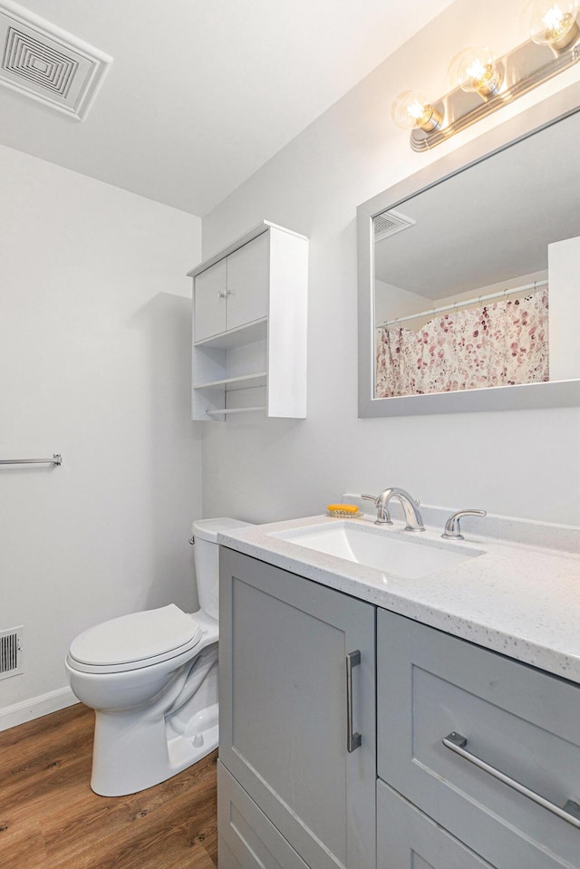 bathroom with wood finished floors, toilet, vanity, and baseboards