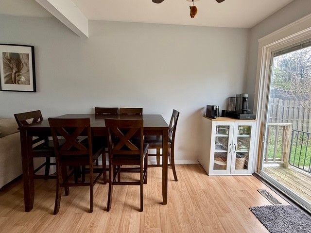 dining space featuring ceiling fan, light wood-style floors, baseboards, beamed ceiling, and visible vents