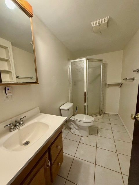 bathroom with toilet, tile patterned floors, a shower stall, and vanity