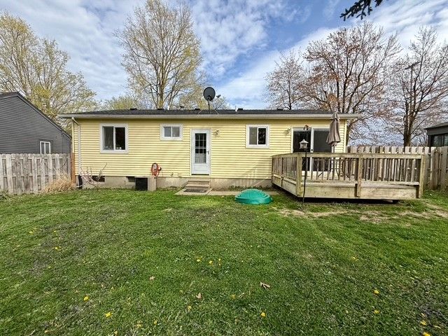 rear view of house featuring entry steps, fence, a yard, and a deck