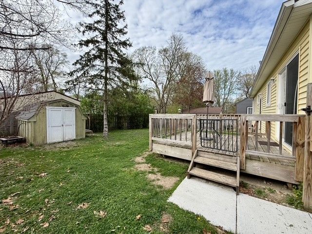 view of yard with a wooden deck, an outbuilding, and a shed