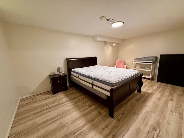 bedroom featuring baseboards, visible vents, and wood finished floors