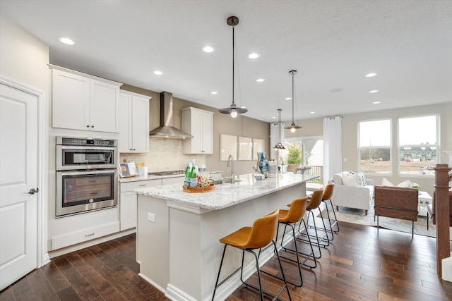 2774 Polson St, Ann Arbor, MI 48105 - kitchen featuring light stone countertops, a kitchen breakfast bar, dark wood-style floors, wall chimney exhaust hood, and a sink