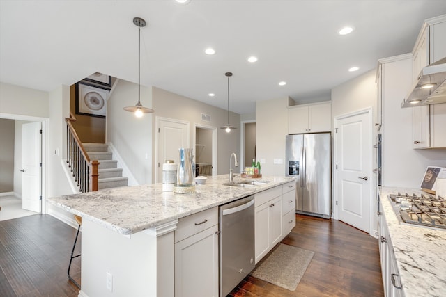 2774 Polson St, Ann Arbor, MI 48105 - kitchen featuring appliances with stainless steel finishes, a center island with sink, a sink, white cabinets, and dark wood-type flooring