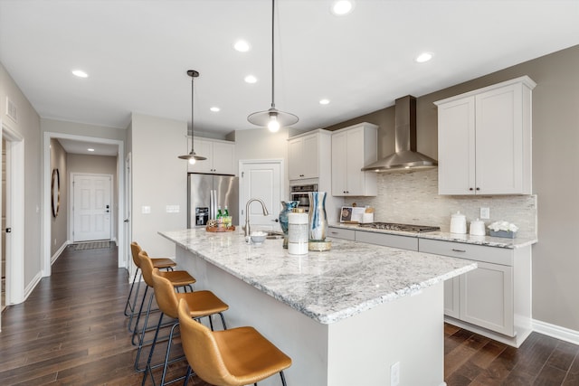 2774 Polson St, Ann Arbor, MI 48105 - kitchen featuring appliances with stainless steel finishes, a breakfast bar, a sink, wall chimney exhaust hood, and dark wood-type flooring