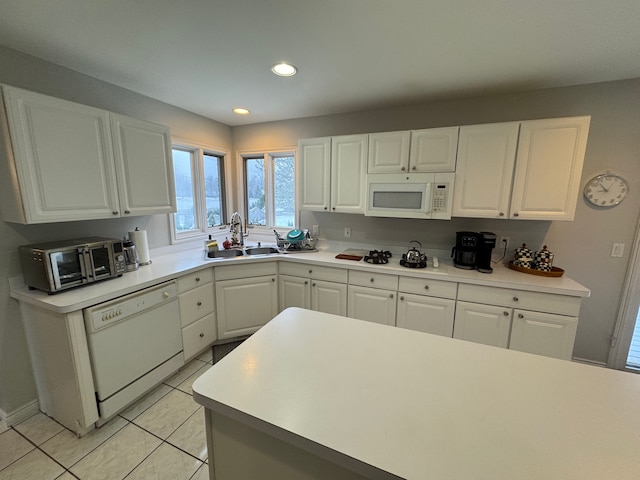 kitchen with a sink, light countertops, white cabinets, and white appliances