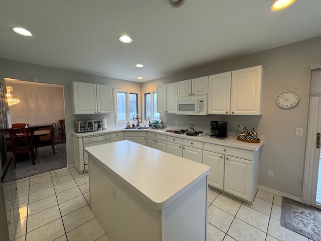 kitchen with white appliances, white cabinetry, and light countertops