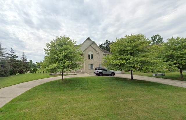 view of property hidden behind natural elements with brick siding and a front lawn