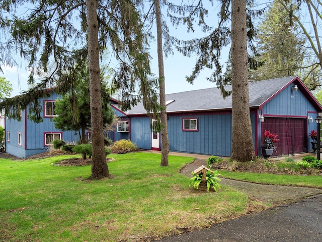 view of front of home featuring a garage, roof with shingles, driveway, and a front yard