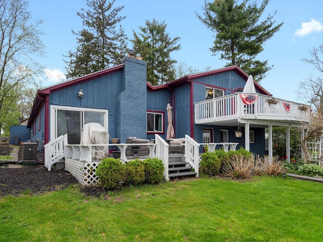 rear view of house featuring a lawn, central AC unit, a chimney, and a deck