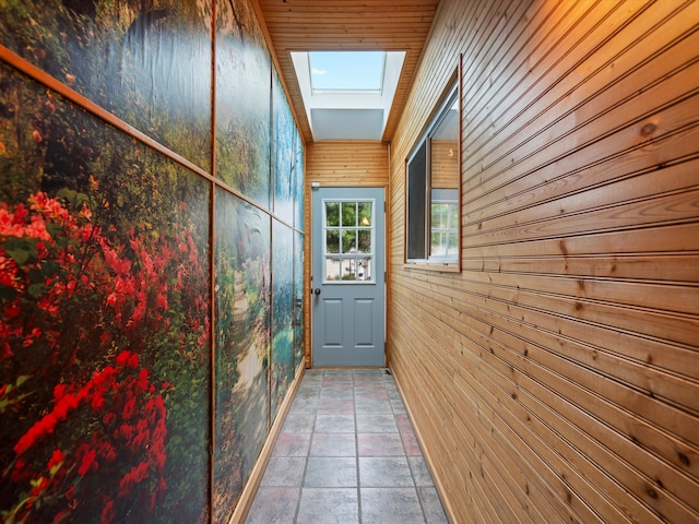 entryway with wood walls, stone finish flooring, and a skylight