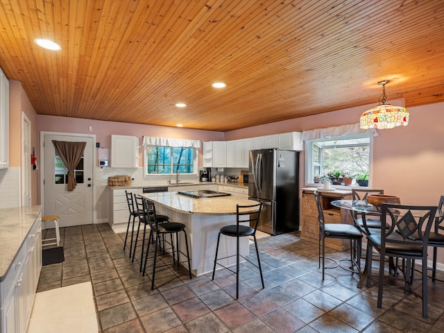 kitchen featuring a sink, freestanding refrigerator, white cabinetry, and a wealth of natural light