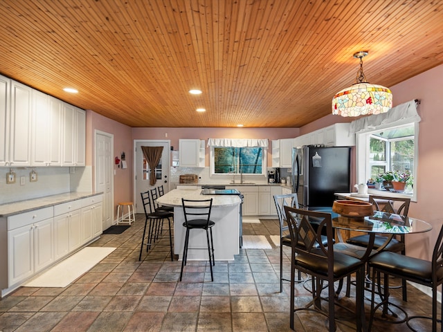 kitchen with a center island, tasteful backsplash, a sink, white cabinets, and freestanding refrigerator
