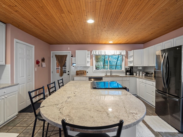 kitchen with open shelves, white cabinets, freestanding refrigerator, and a sink