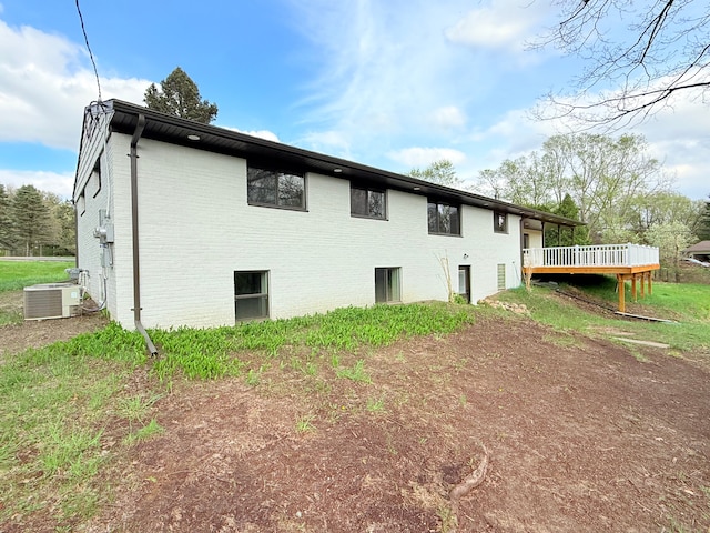 view of property exterior with brick siding, a wooden deck, and cooling unit