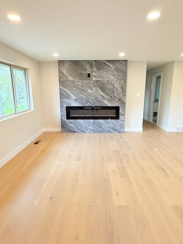 unfurnished living room with recessed lighting, baseboards, wood finished floors, and a fireplace