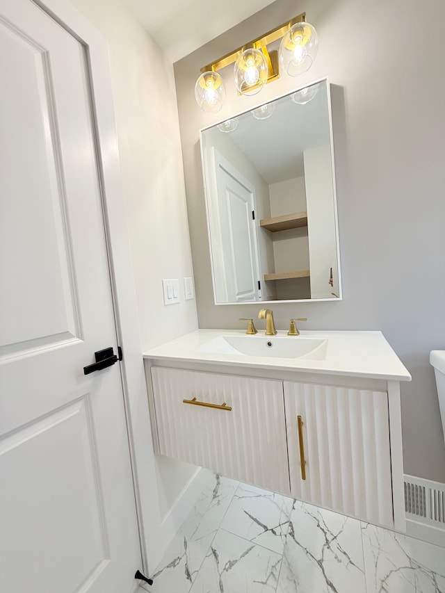 bathroom with toilet, marble finish floor, and vanity