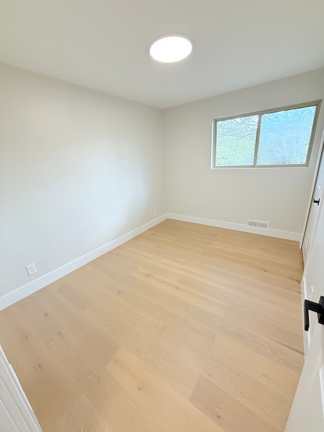 empty room with baseboards, light wood-style flooring, and visible vents