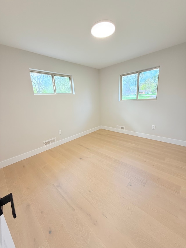 unfurnished room with visible vents, light wood-style flooring, and a healthy amount of sunlight