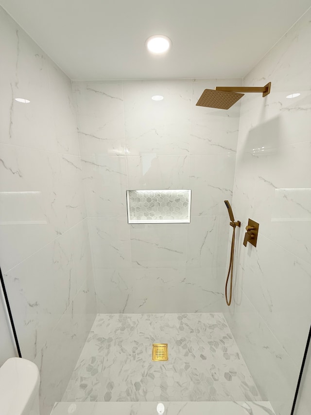bathroom featuring toilet and a marble finish shower