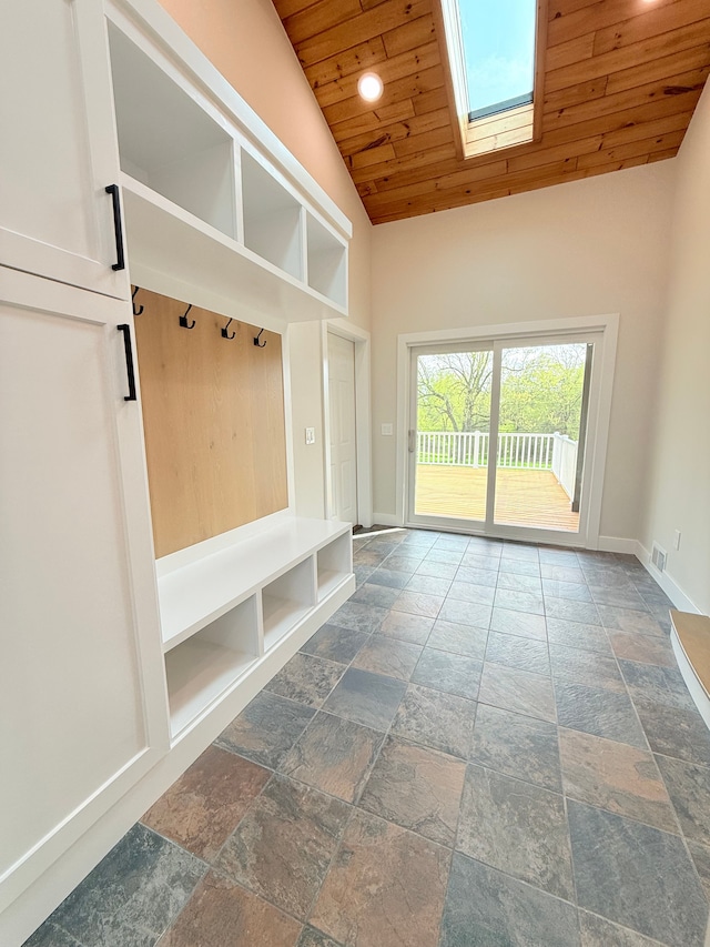 mudroom with high vaulted ceiling, baseboards, wooden ceiling, a skylight, and stone tile flooring