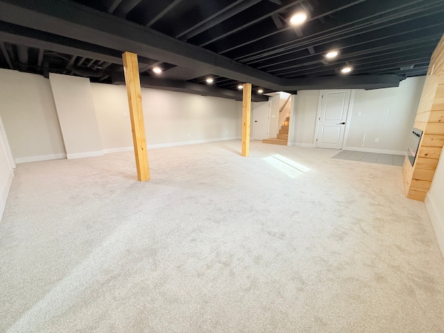 finished basement with stairway, baseboards, and carpet flooring