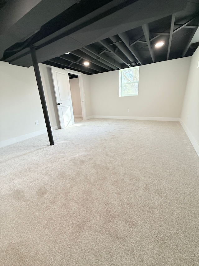 basement featuring baseboards and light carpet