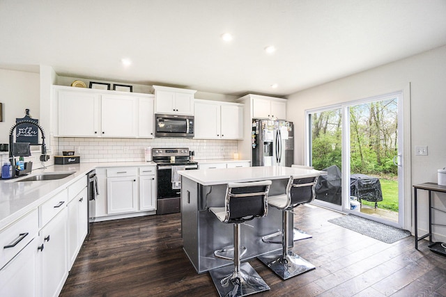 kitchen with a sink, light countertops, a breakfast bar area, stainless steel appliances, and backsplash