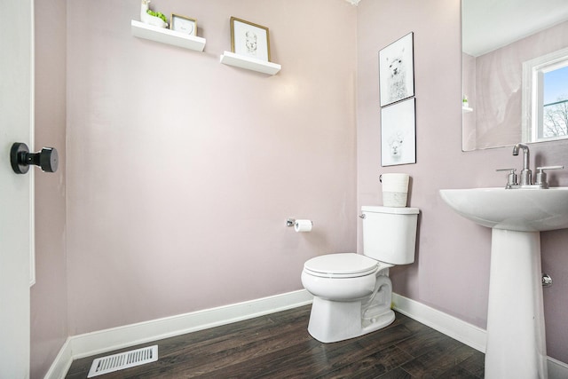 half bath featuring visible vents, baseboards, wood finished floors, and toilet