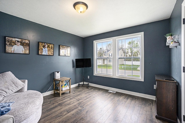living area with dark wood-style flooring, baseboards, and visible vents