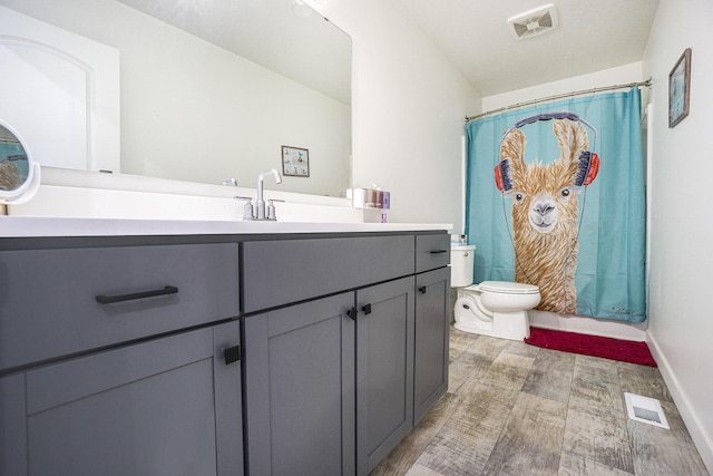 bathroom featuring visible vents, wood finished floors, toilet, and vanity