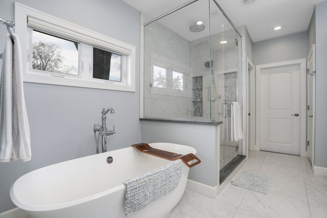 bathroom with marble finish floor, recessed lighting, a shower stall, a freestanding bath, and baseboards