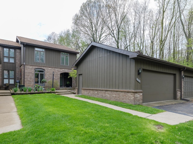view of front of home featuring board and batten siding, driveway, a front yard, brick siding, and an attached garage