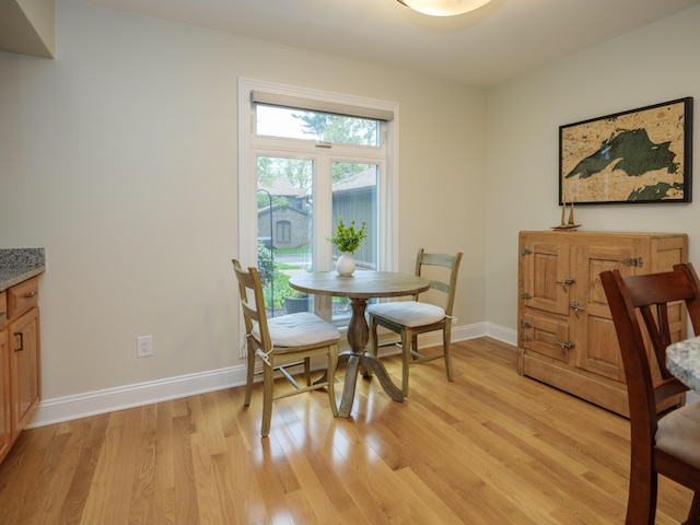 dining space featuring light wood-type flooring and baseboards