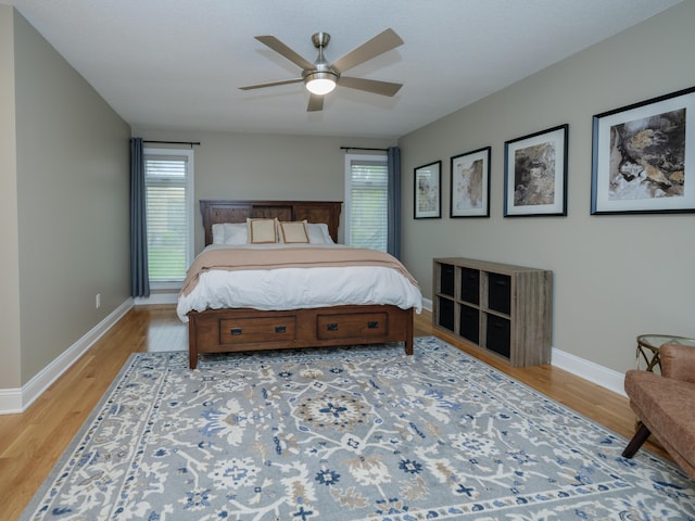 bedroom with a ceiling fan, baseboards, and light wood-type flooring