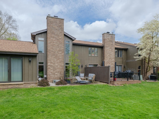 back of property featuring board and batten siding, central AC, a yard, and a chimney