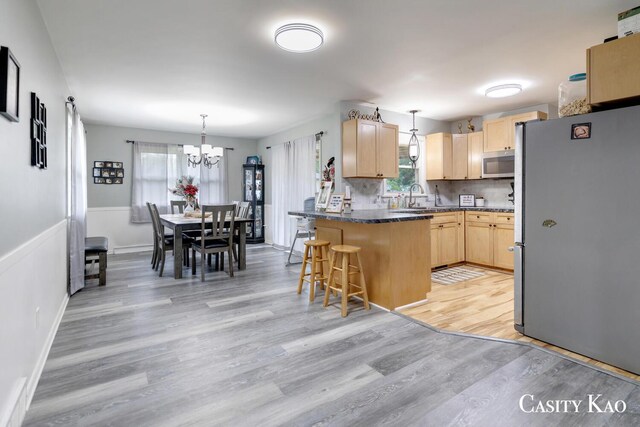 7116 Linden Ave SE, Grand Rapids, MI 49548 - kitchen with light brown cabinetry, stainless steel appliances, a peninsula, and light wood-style flooring